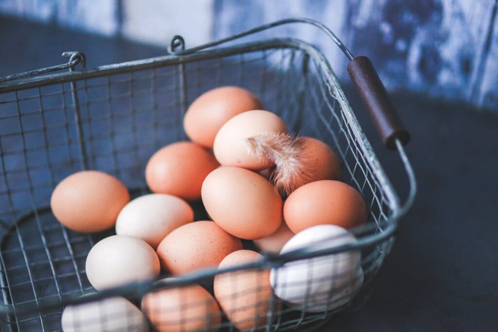 metal-easter-eggs-basket A close-up of farm fresh eggs in a metal basket, featuring a delicate feather for a rustic touch.